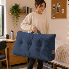 Blue wedge pillow cushion with tufted buttons, shown being placed on a bed
