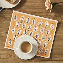 Dishcloth with orange background, cream border, and brown leaf pattern