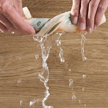 Dishcloth with small green leaf print, being stretched as water pours