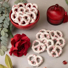 White chocolate heart pretzels with dark sprinkles, with red rose nearby