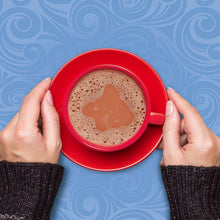 Red mug of hot cocoa with foamy surface, held by hands