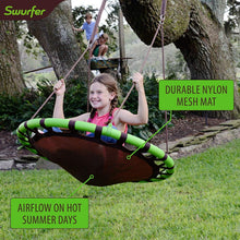 Kid on green-and-black saucer tree swing with brown nylon mesh mat and rope