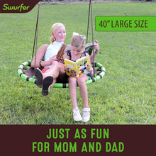 Two kids on green saucer tree swing with brown padded mat and rope suspension