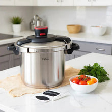 Stainless steel pressure cooker with red lid control and black handles