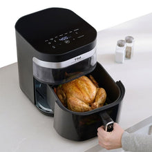T-fal air fryer with open basket and whole roasted chicken being removed