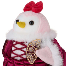 Plush fabric bird with white face, yellow beak, burgundy outfit, and gold emblem.