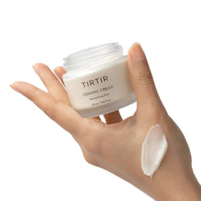 TIRTIR Ceramic Cream jar held in hand with white cream swatch on skin.