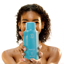Person holding turquoise TPH Hustle & Co rich co-wash conditioner bottle