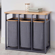 Three gray fabric laundry bins on a bamboo-top laundry station with open compartments