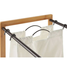 Bamboo laundry station with hanging white laundry bags on black metal bars
