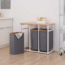 Gray fabric laundry bins on a bamboo-top laundry station with white frame and open side