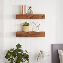 Two floating walnut shelves on a white wall, farmhouse style, with decorative items.