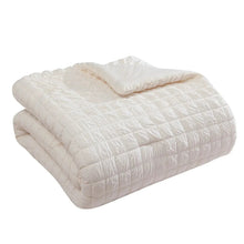 Folded white quilted cotton comforter with crinkle-style stitched texture