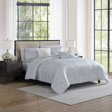 Light grey jacquard comforter set on bed with layered shams and accent pillows