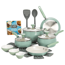Sage green ceramic non-stick cookware set with pots, pans, glass lids, and utensil pieces
