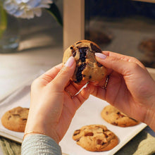 Soft baked dark chocolate chunk cookie piece held between hands