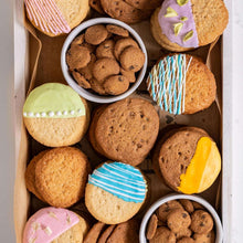 Assorted frosted cookies in a cardboard box, including chocolate-chip walnut cookies