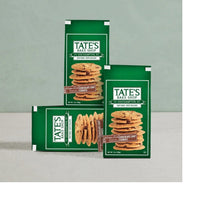 Thin chocolate chip cookies in green bags, shown with cookie stacks on display