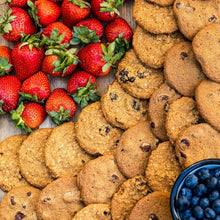 Assorted cookies with white filling alongside strawberries and blueberries, close-up