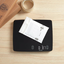 Black digital kitchen scale with a packaged ingredient resting on the platform
