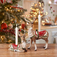 Close-up of deer candle holder with red saddle and two lit candles