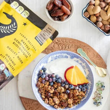 Organic pitted dates in bowls with granola and fruit on a patterned plate