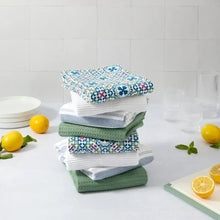 Stack of patterned kitchen towels in teal, green, and white, neatly folded.
