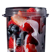 Plastic blender cup with creamy white coconut mixture and mixed berries