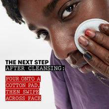 Person applying facial toner to face with a cotton pad after cleansing