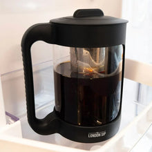 Black cold brew coffee maker with transparent brewing chamber and stainless filter basket