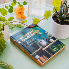 Hardcover gardening guide book lying on table with teal cover and plant illustrations
