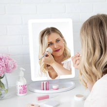 Lighted makeup mirror on round base, reflecting a person applying makeup