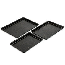 Three black nonstick sheet pans with textured surface and sloped corners