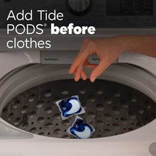 Laundry washer drum with Tide PODS detergent pacs placed before clothes