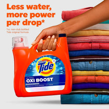 Tide Ultra Oxi Boost detergent bottle held in front of folded colorful clothes.