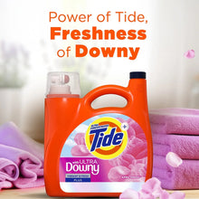 Orange liquid laundry detergent bottle with Downy logo, April Fresh label, on towels