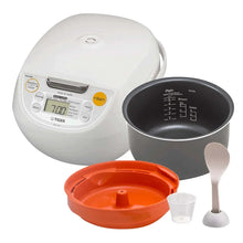 White rice cooker with inner pot, orange lid, spatula and measuring cup