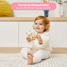 Baby holding cream bunny silicone rattle with teardrop-shaped hole cutouts.