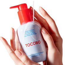 Tocobo cleansing oil bottle held by hands with red pump and light blue label