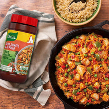 Tomato chicken bouillon jar with red cap beside bowl of seasoned chicken mix