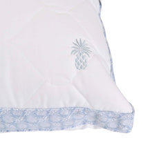 White quilted pillow corner with pineapple emblem and light blue patterned edge