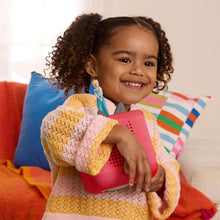 Child smiling while holding a red Toniebox 2