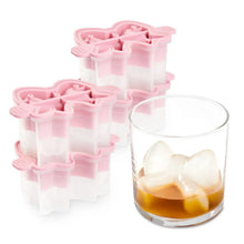 Silicone holiday bow ice molds, pink with clear compartments, beside glass of bow ice