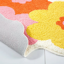 Bath mat corner close-up with gray backing and orange, pink, and yellow flowers