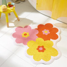Bath mat with pink, orange, and yellow flower design on white loop pile