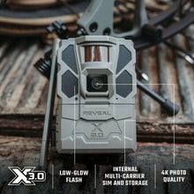 Gray trail camera front close-up with lens window and REVEAL marking