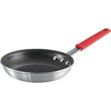 Small nonstick frying pan with black interior and red handle, angled close-up view.