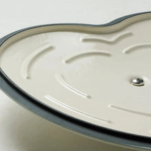 Cream enameled heart-shaped dutch oven interior with pink rim and side handle