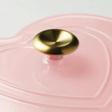 Pink enameled dutch oven lid with gold knob and heart-shaped raised lid pattern