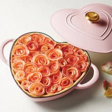 Heart-shaped dutch oven in pink holding spiral-shaped food with sauce
